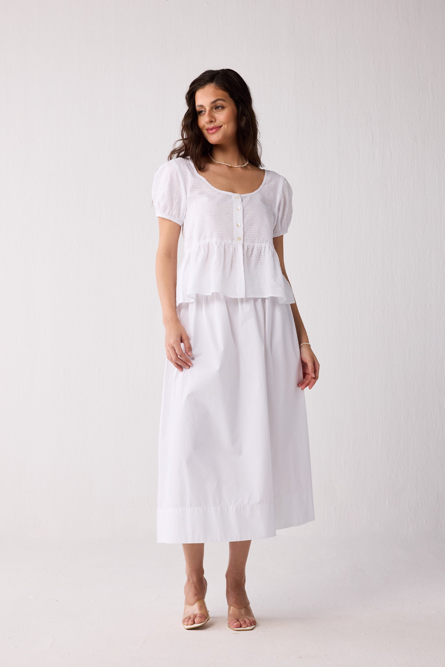 A woman wearing a white top on a plain background