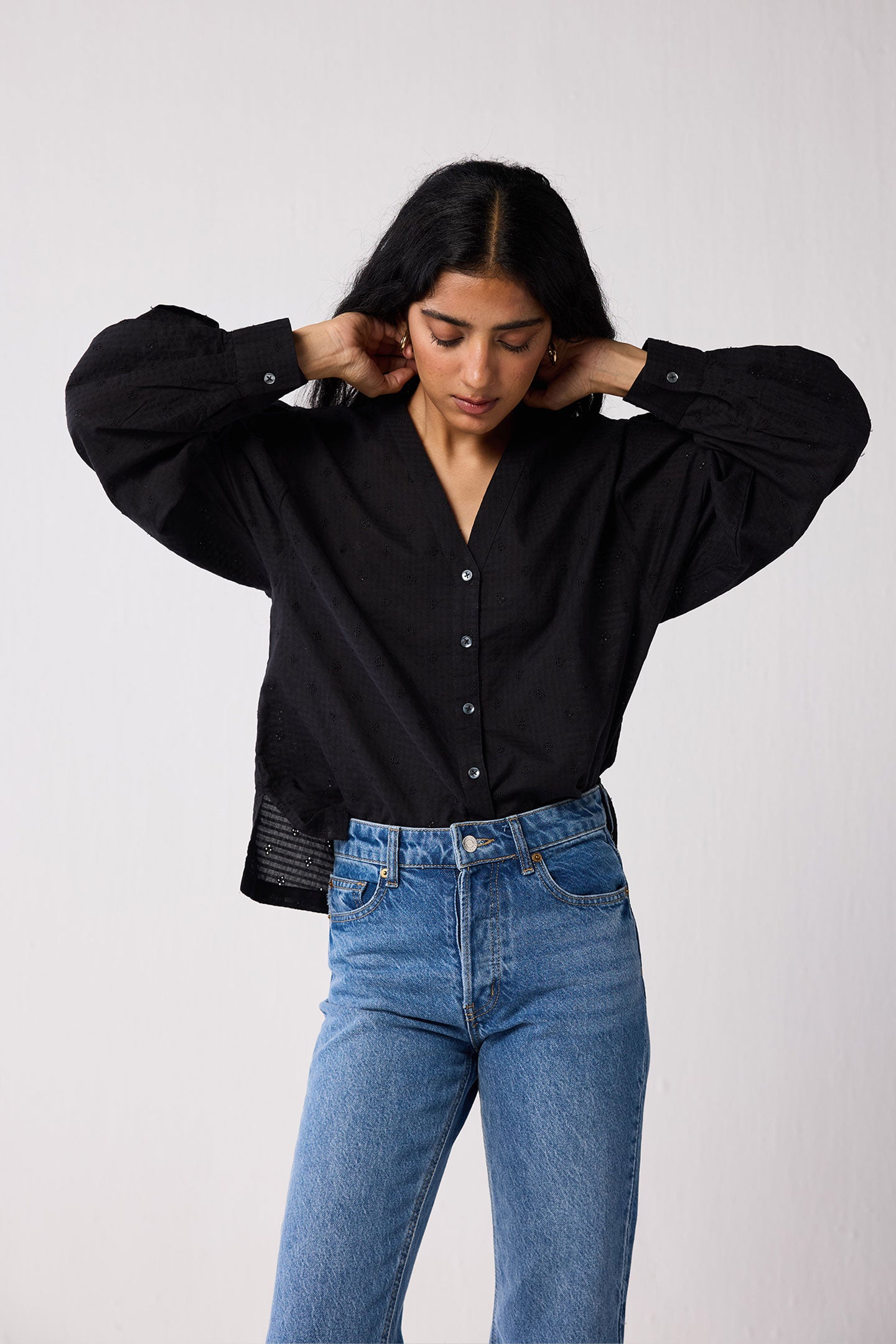 Person wearing a black shirt and blue jeans against a white background