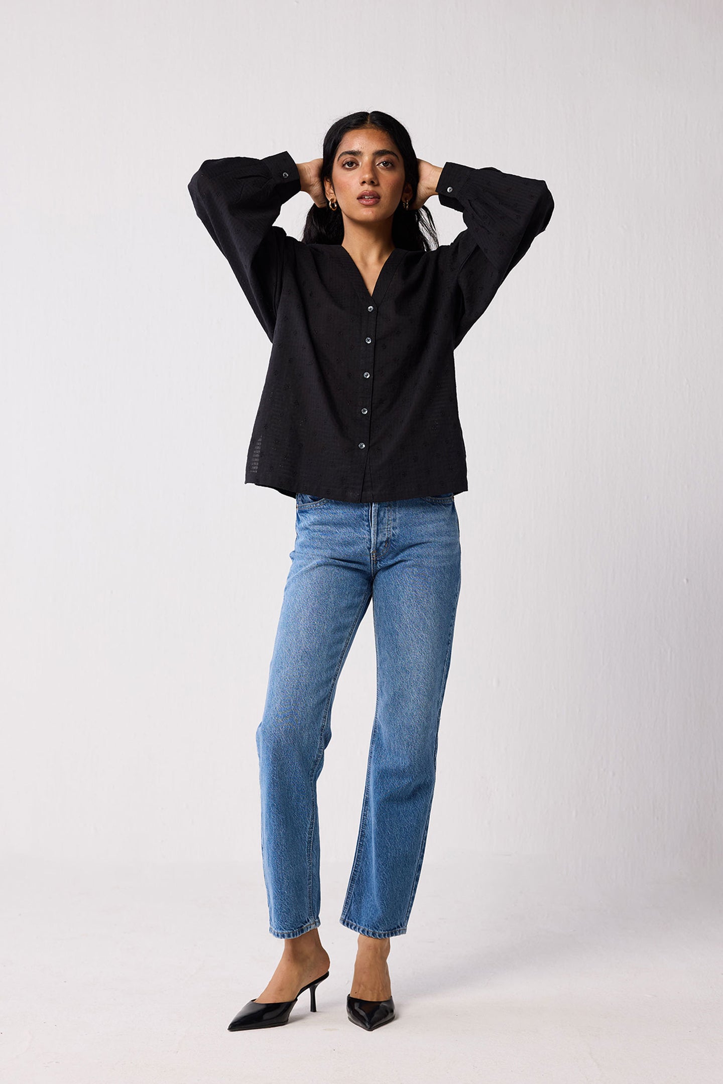 Person wearing a black shirt and blue jeans on a white background