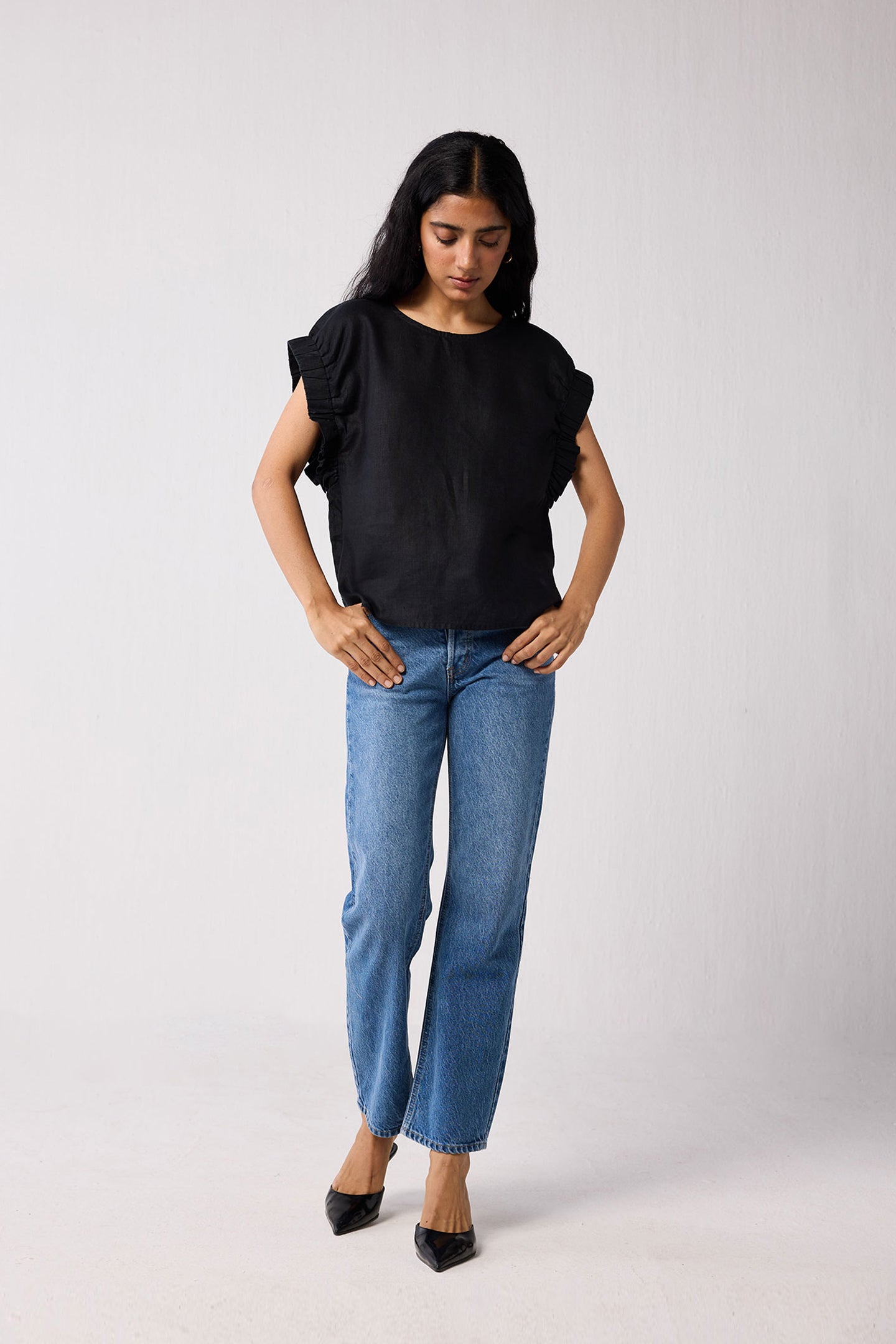 Woman wearing a black top and blue jeans on a white background