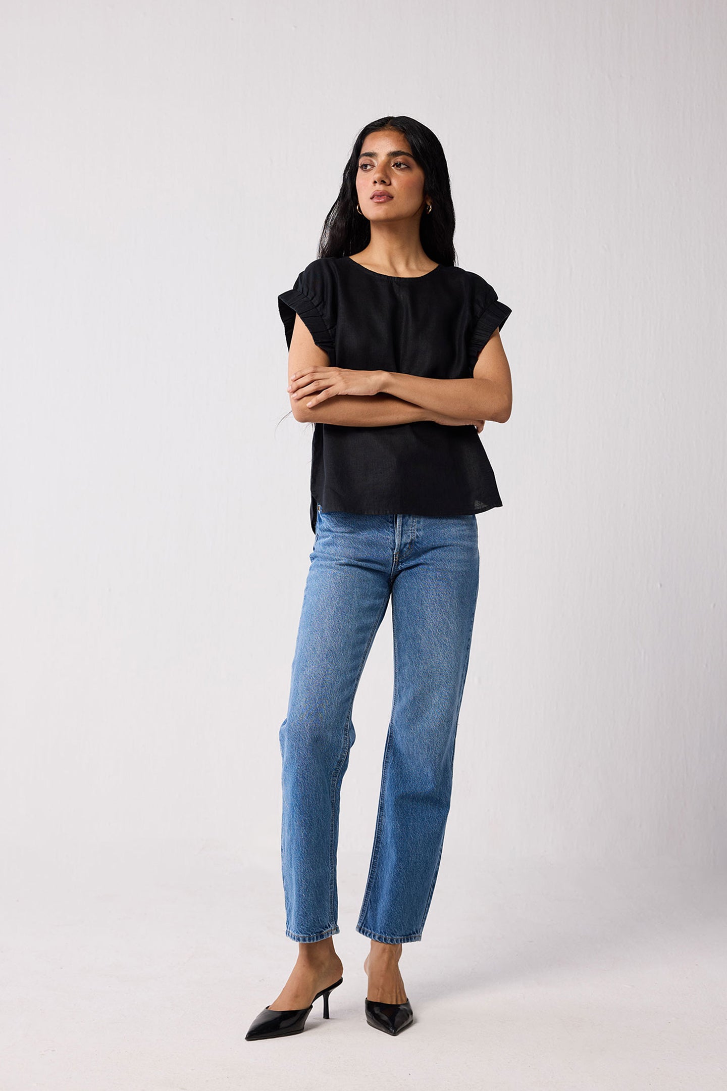 Woman wearing a black top and blue jeans on a white background