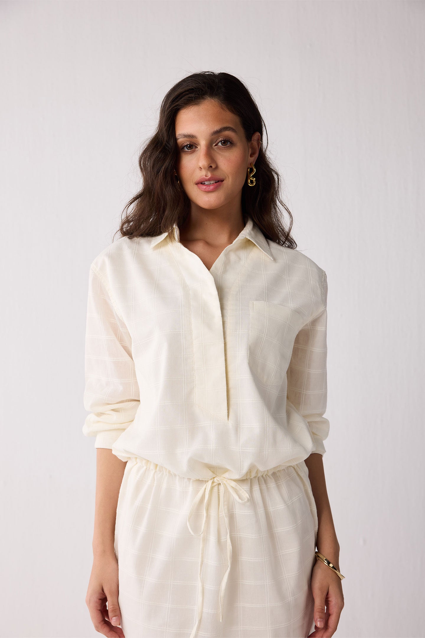 Woman wearing a white outfit against a plain background