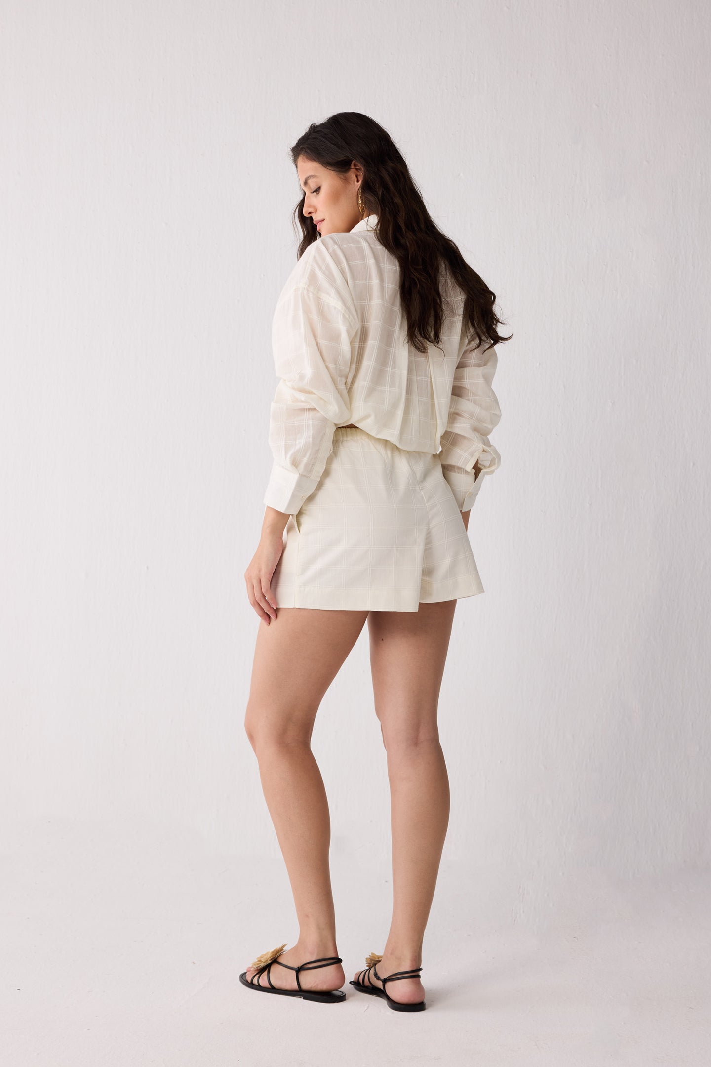 A woman wearing an off-white colored outfit on a white background