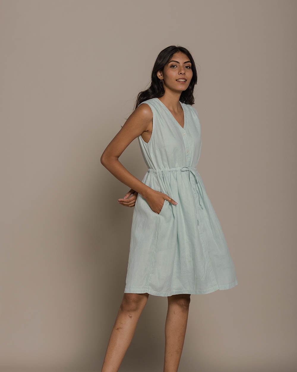 A woman standing wearing a blue and white striped sleeveless knee-length dress with a V-neckline.