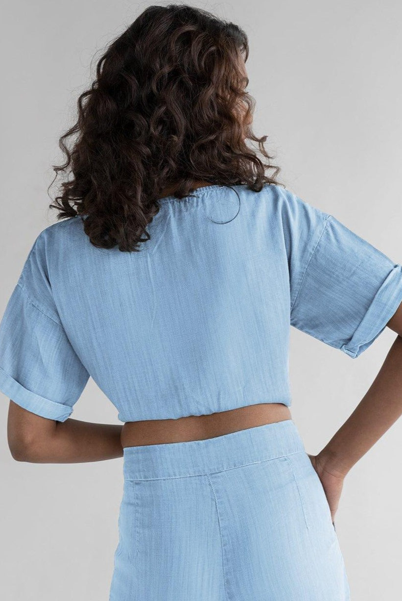 Back view of Twist and Sway Top in Blue by Reistor, featuring a relaxed cropped silhouette, rolled short sleeves, breathable fabric, and effortless everyday style.