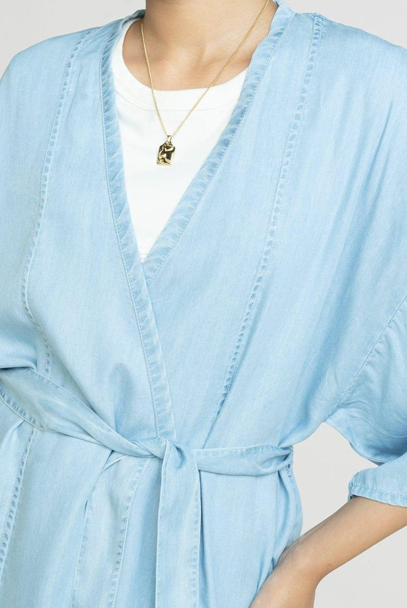 Close-up of the Reistor Wrapped in Happiness Overlay in Ocean Blue, featuring a flattering V-neckline, self-tie waist and lightweight fabric for chic layering.