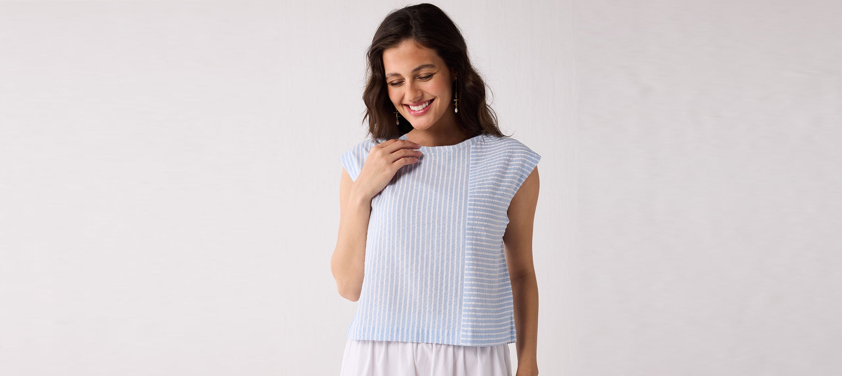 Woman wearing a light blue sleeveless textured top styled for effortless work-to-weekend wear, photographed against a minimal background.