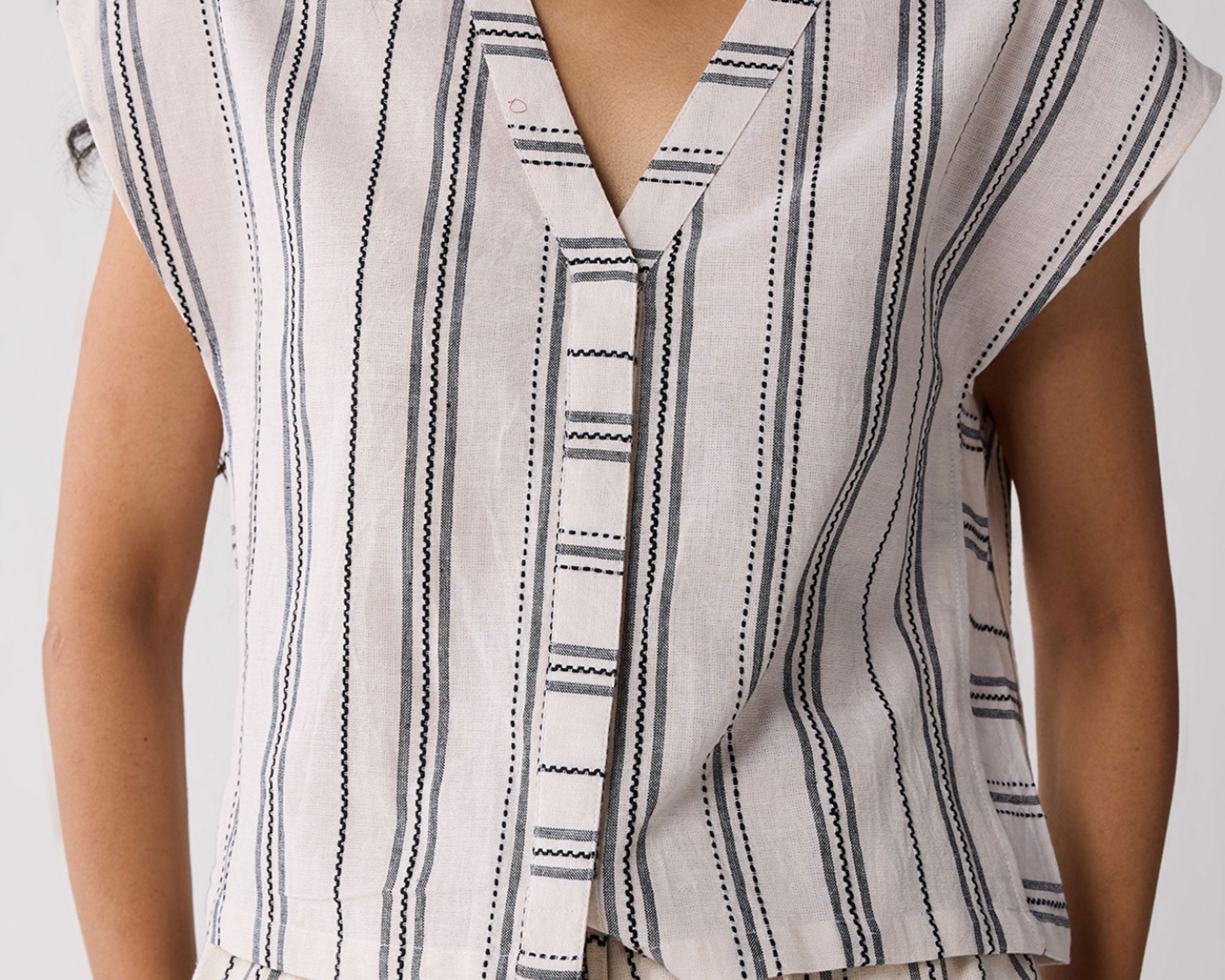 Striped sleeveless top worn by a person on a plain background