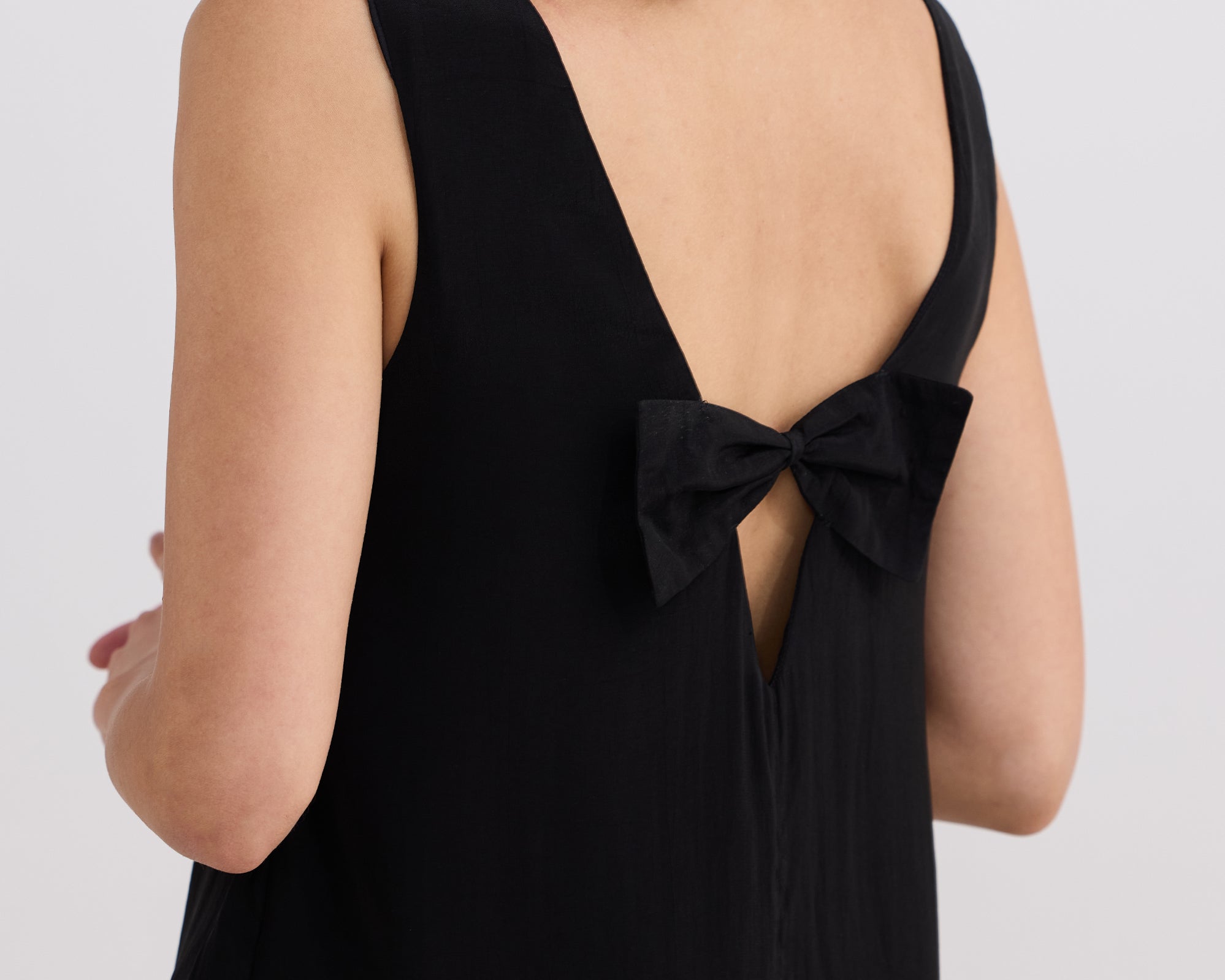 Black dress with a bow detail on a plain background