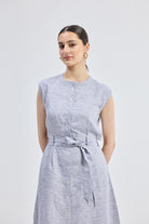 Model wearing the Reistor Back Cut Out Linen Dress in a light blue striped pattern, featuring a sleeveless design, button-down front, and tie-waist detail.