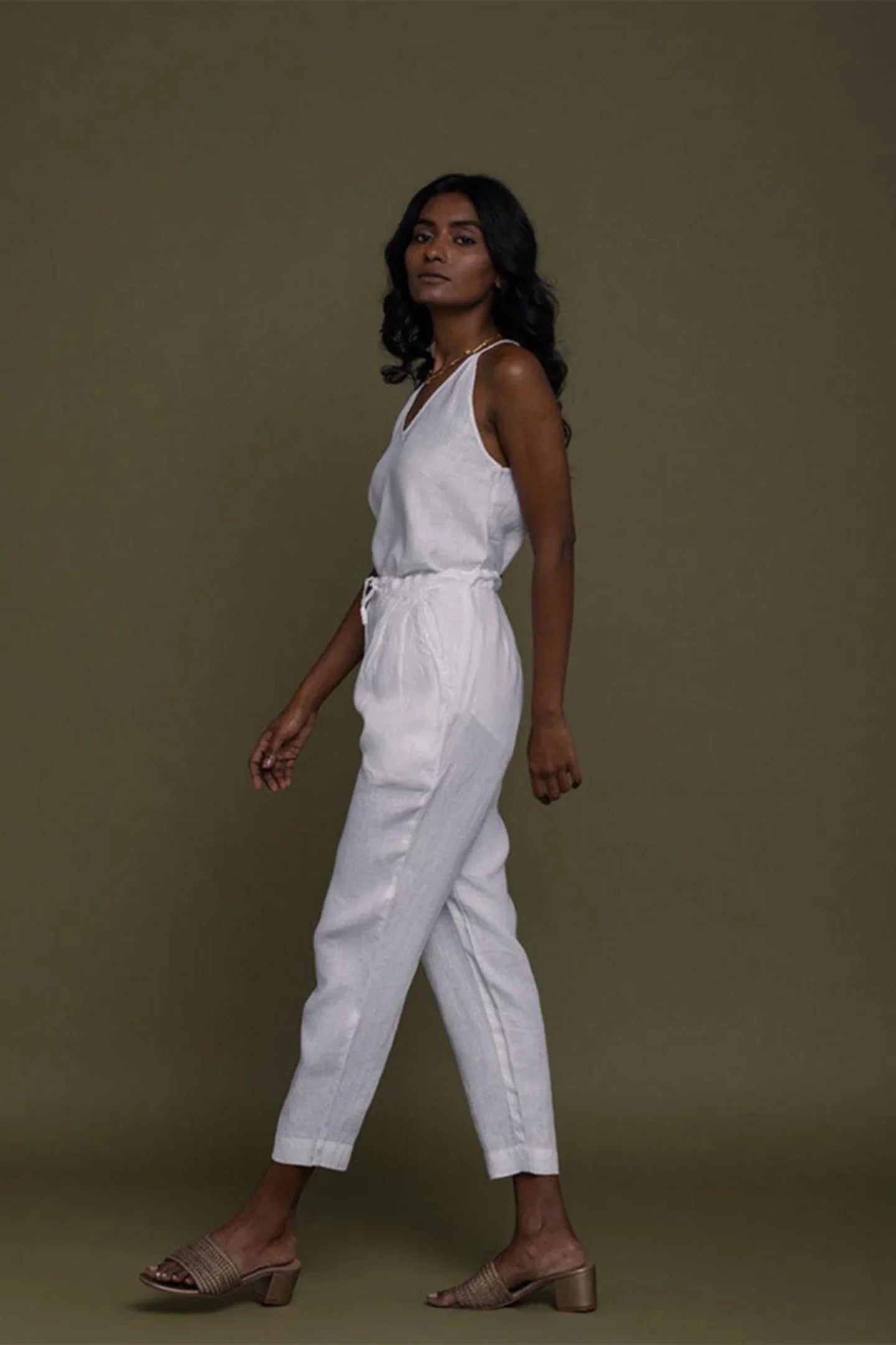 Reistor sleeveless white belted jumpsuit with tapered legs, side profile in sustainable women's everyday fashion.