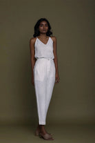 Reistor white sleeveless V-neck top with tapered pants and tie-waist detail, sustainable women's fashion look.