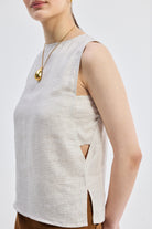 Close-up side view of reistor Boat Neck Top in Checkered Linen, sleeveless beige linen top featuring subtle check pattern, armhole detail, and side slit.