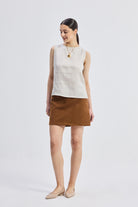 Full-length view of model wearing reistor Boat Neck Top in Checkered Linen, sleeveless beige checkered linen top styled with a brown skirt for a relaxed everyday look.