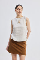 Model wearing reistor Boat Neck Top in Checkered Linen, sleeveless beige checkered linen top with boat neckline and relaxed silhouette, paired with a brown skirt.