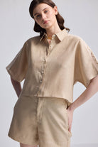 Front view of Boxy Shirt with Lace by reistor in beige, featuring a relaxed boxy fit, button-down front, collared neckline, and delicate lace detailing on the short sleeves, paired with matching shorts against a neutral background.