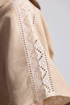 Close-up of the delicate white embroidered lace detailing on the sleeve and shoulder of the neutral beige Boxy Shirt with Lace by Reistor.