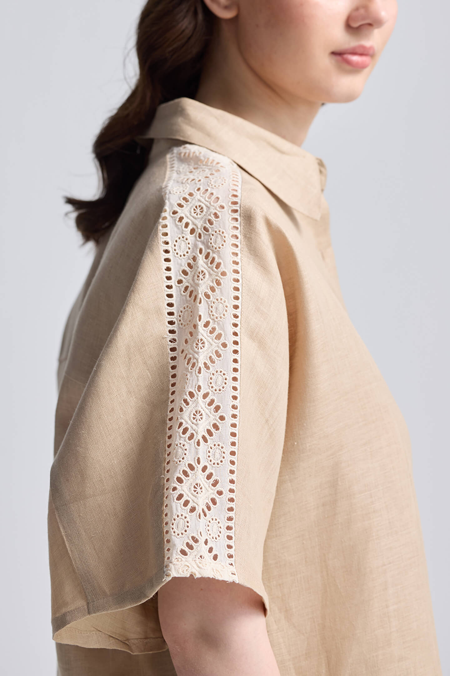 Front view of a woman wearing the beige Reistor Boxy Shirt with Lace, featuring a button-down front, collar, and relaxed fit.