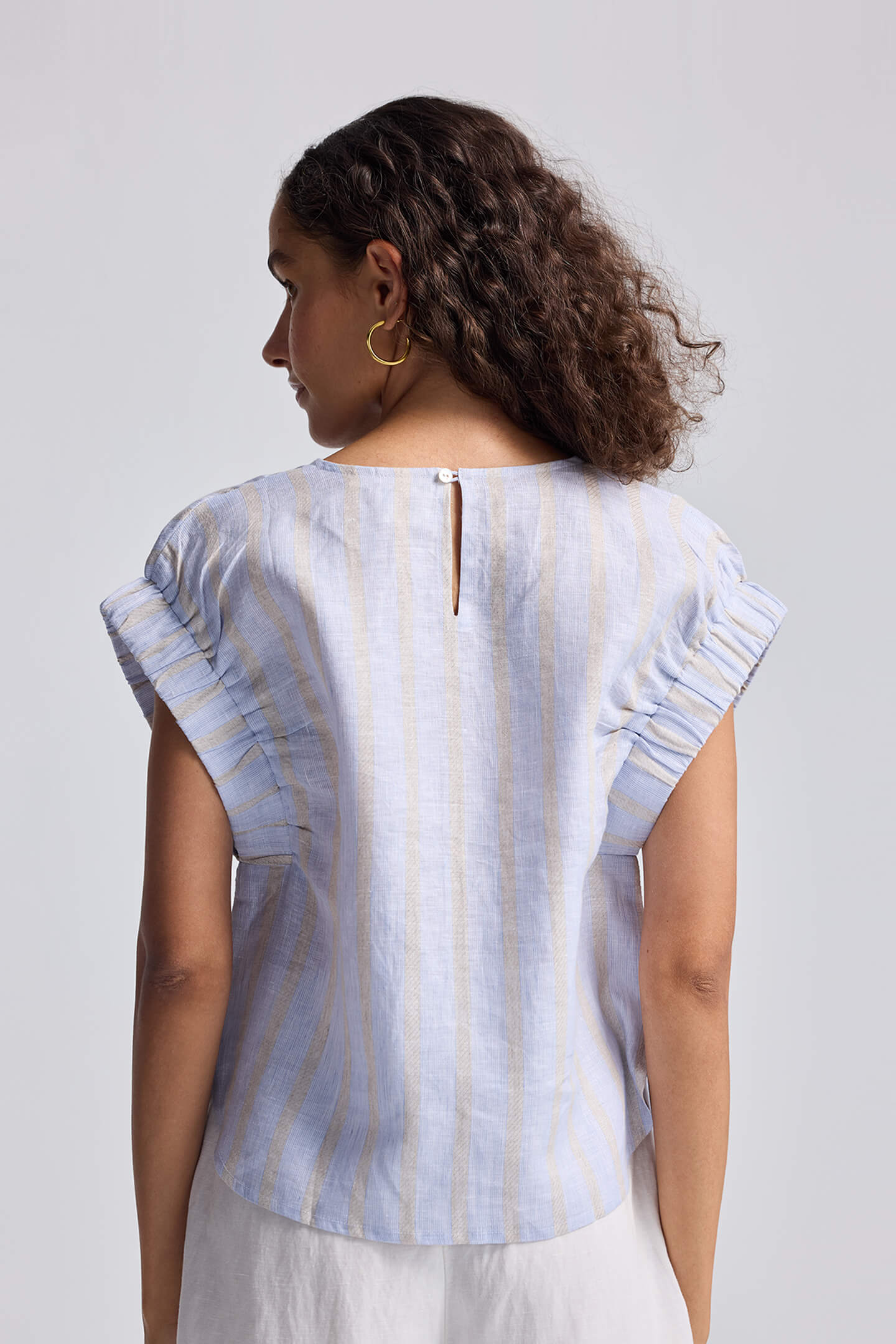 Rear view of the reistor Boxy Top with Sleeve Detailing, showing the blue and white textured linen stripes and ruffled sleeve edges.