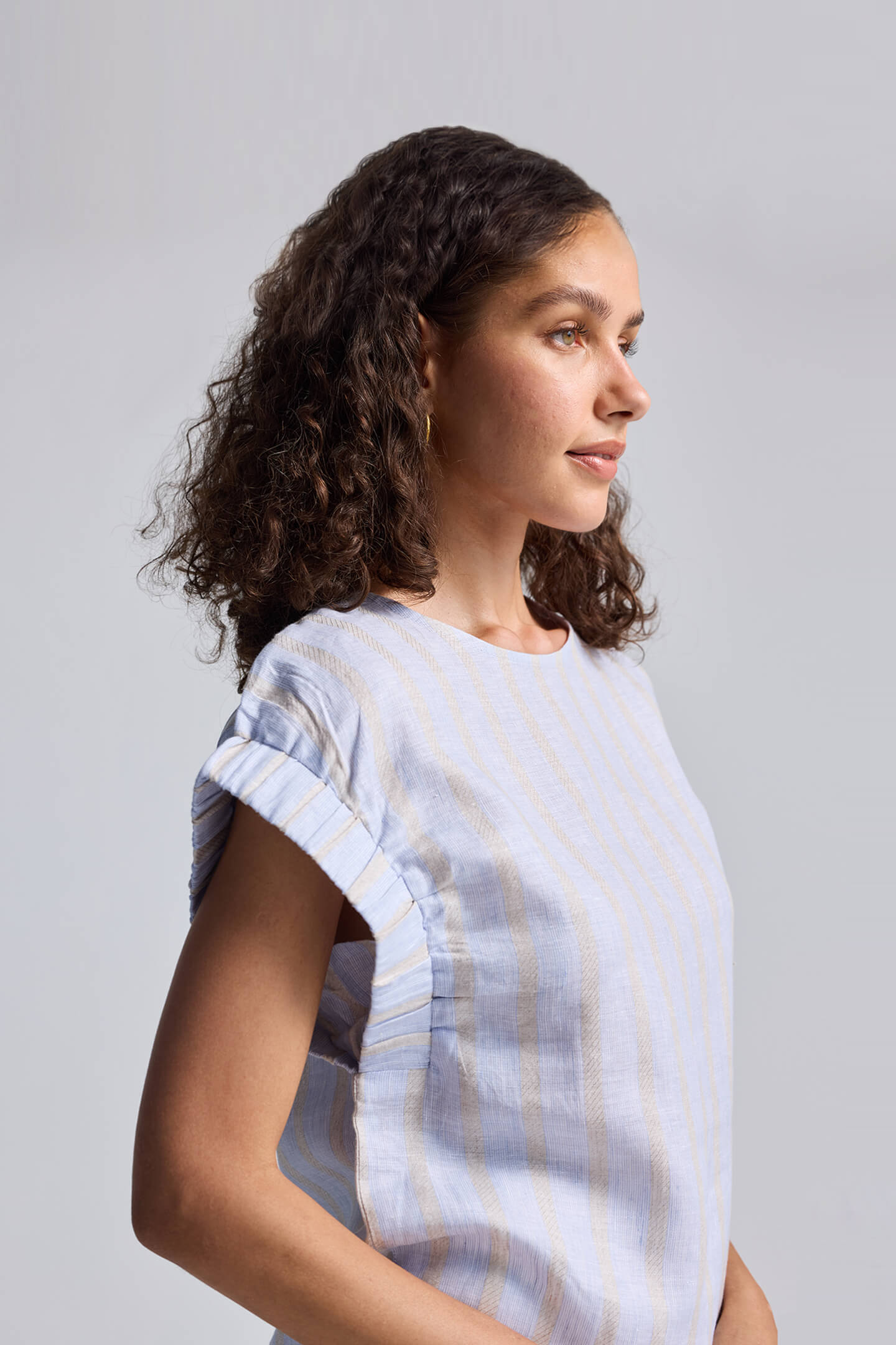 Rear view of the reistor Boxy Top with Sleeve Detailing featuring light blue and white textured stripes and a small back button closure.