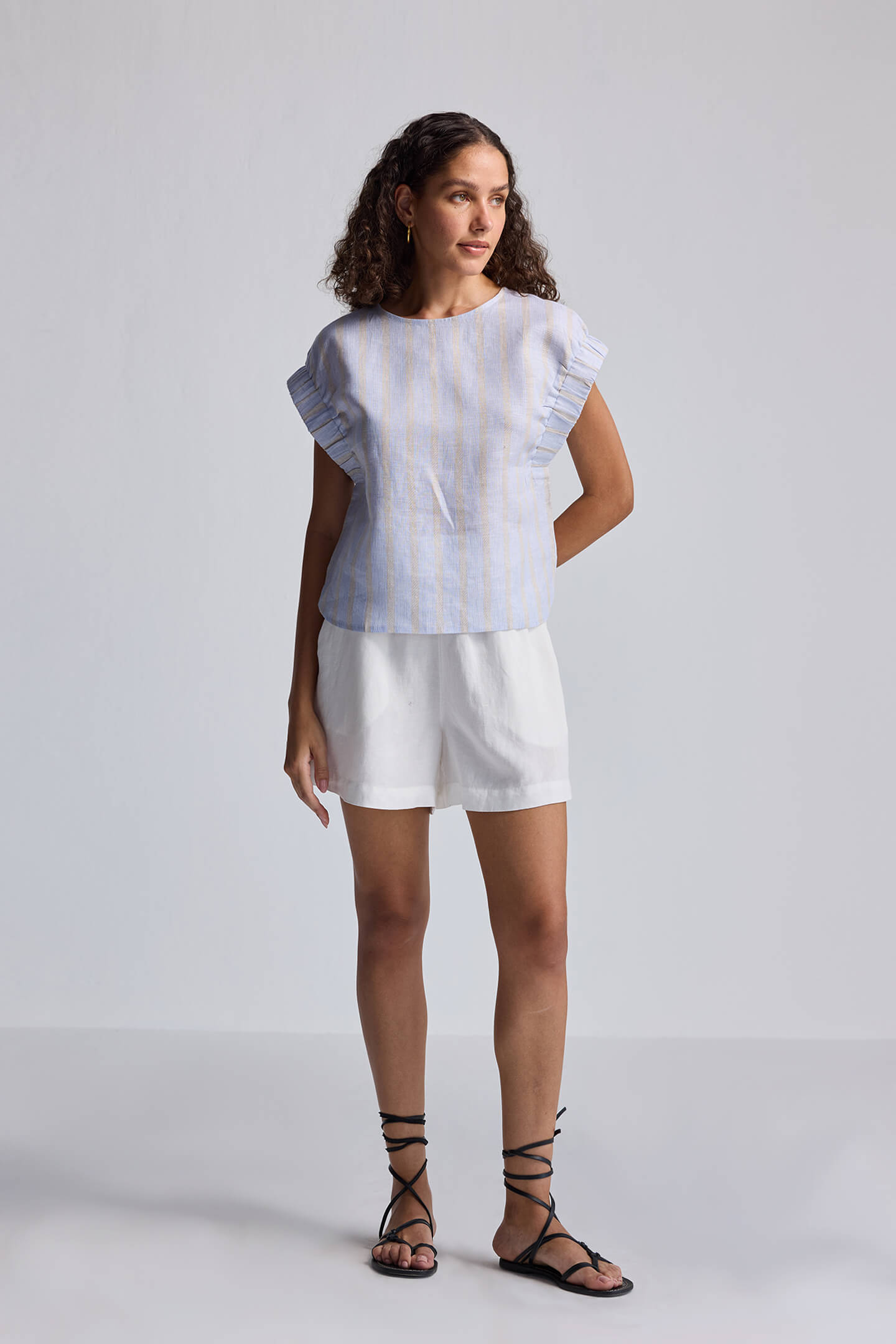 Rear view of the striped reistor Boxy Top with Sleeve Detailing featuring blue and beige vertical lines and a back button-loop closure.
