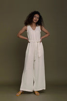 Woman wearing a Reistor white sleeveless jumpsuit against a brown background.