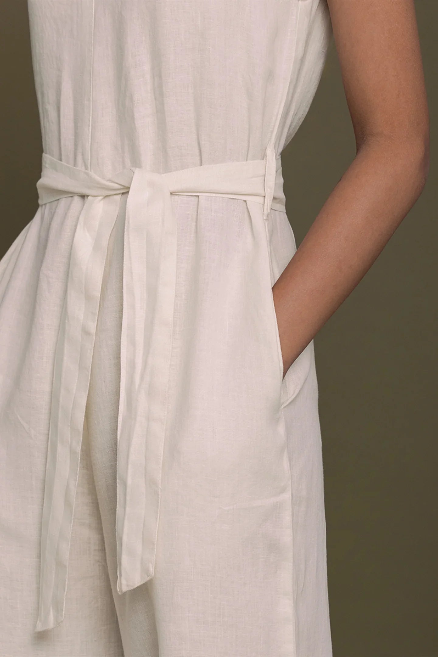 Close-up of a Reistor beige dress with a belt on a plain background.