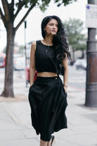 Woman wearing the Breezy Summer Set in Black by reistor, featuring a sleeveless crop top and flowy skirt, styled for a chic urban summer look.