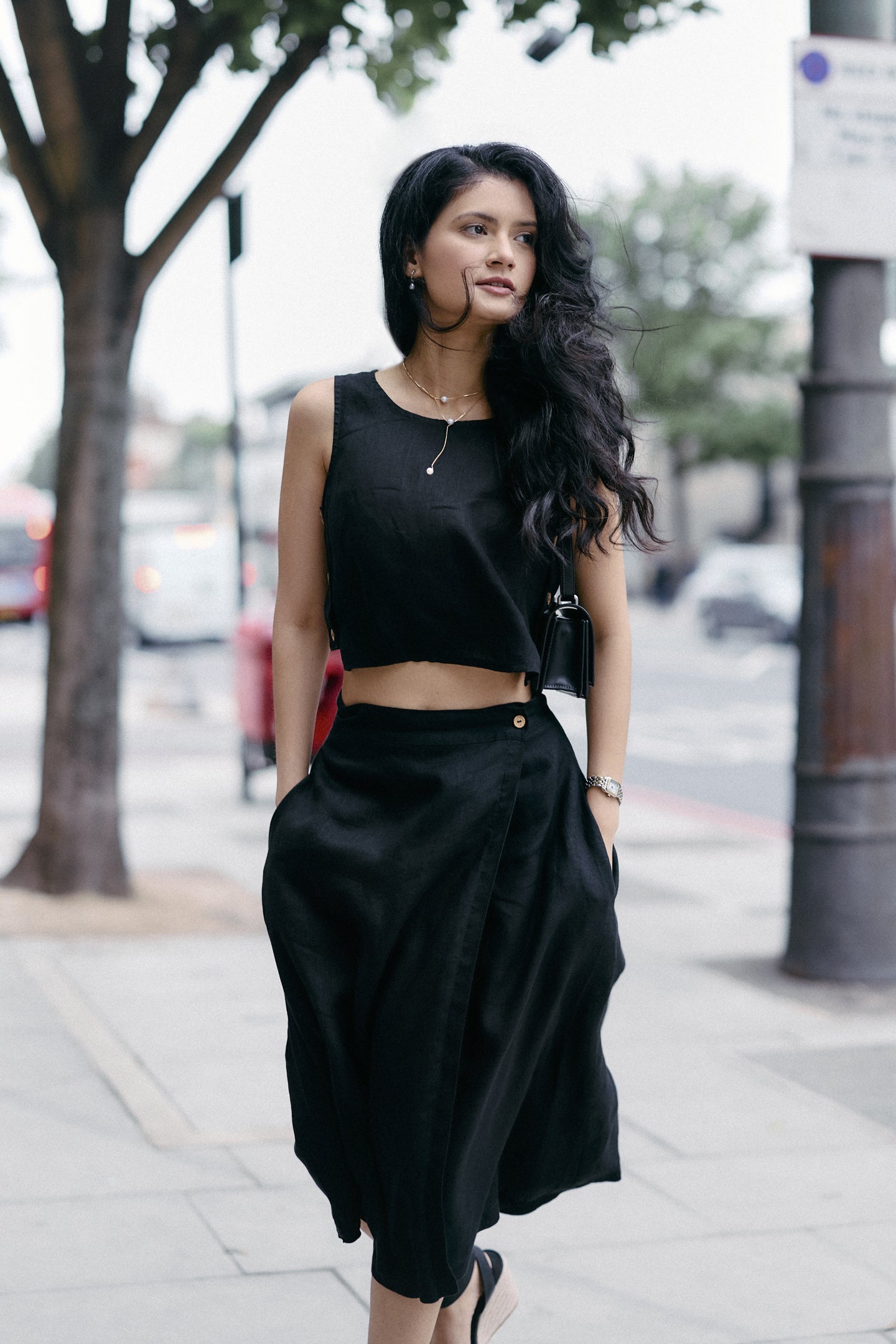 Woman wearing the Breezy Summer Set in Black by reistor, featuring a sleeveless crop top and flowy skirt, styled for a chic urban summer look.