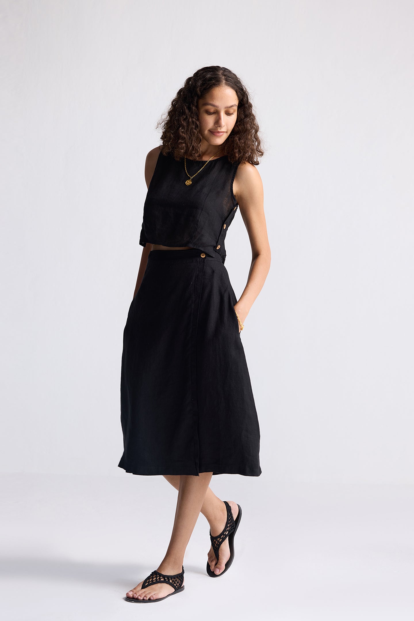 Model wearing Reistor Breezy Summer Set in Black, featuring a sleeveless crop top and flowy midi skirt styled with flat sandals for a minimalist summer look.
