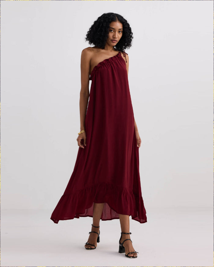 Woman wearing a burgundy one-shoulder dress on a white background