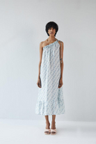 Woman wearing the Reistor Dancing in the Moonlight Dress, a light blue patterned one-shoulder sustainable dress, perfect for summer vacations, brunches, and resort wear.