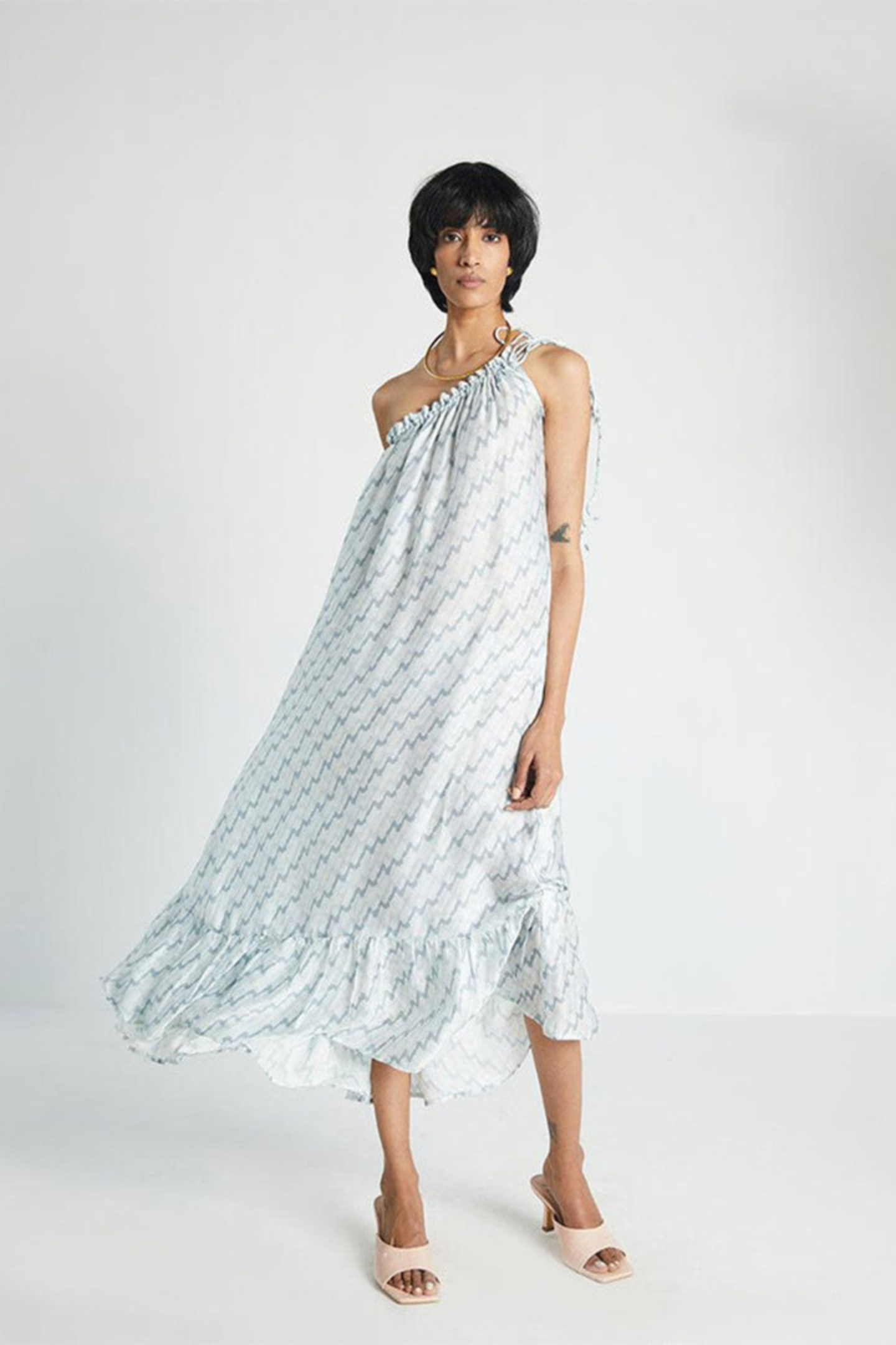 Woman wearing the Reistor Dancing in the Moonlight Dress, a light blue one-shoulder sustainable dress with a flattering silhouette, perfect for summer outings and vacations.
