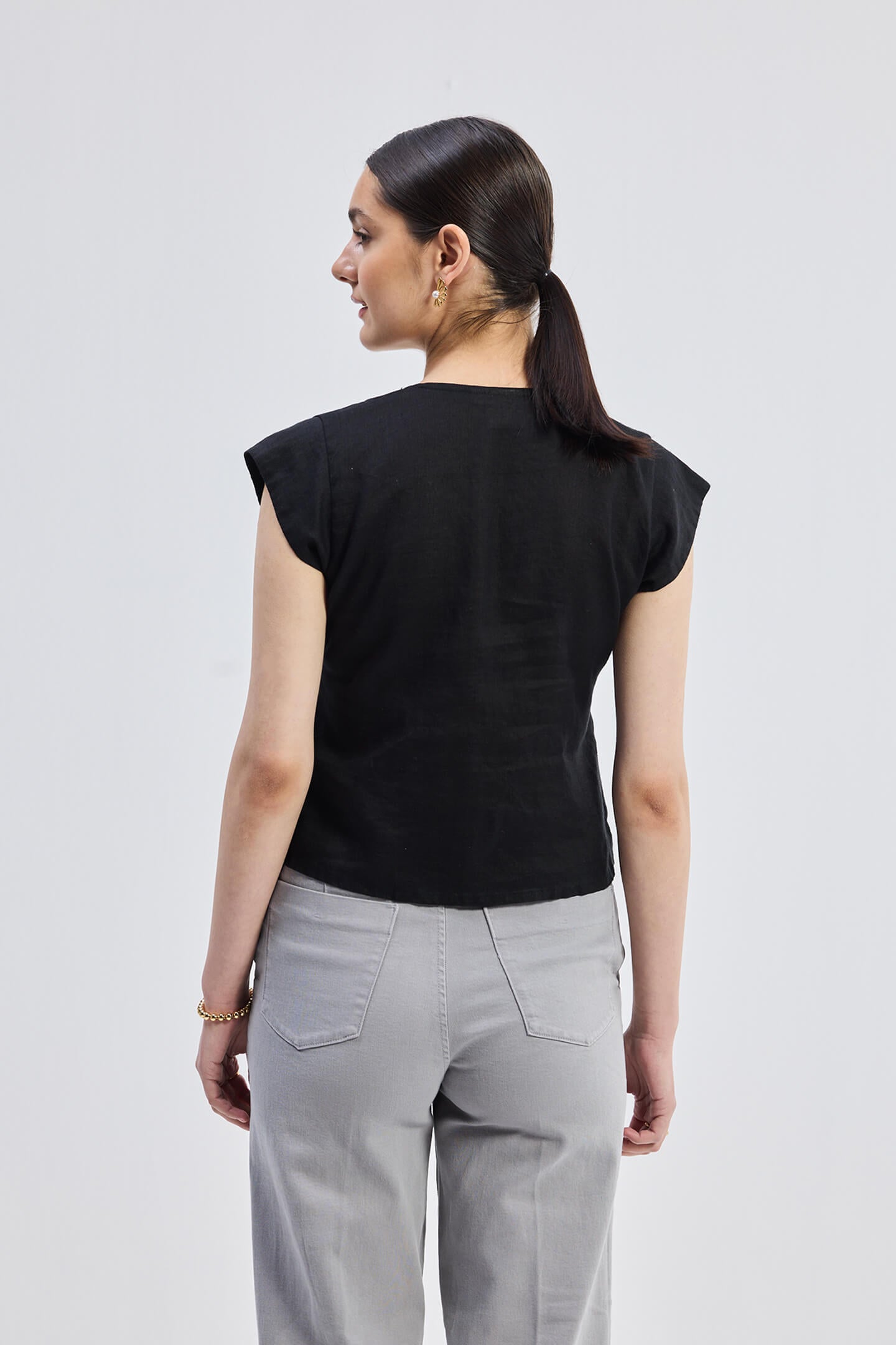 Deep V-neck short top in Black by reistor featuring cap sleeves, a relaxed fit silhouette, and breathable lightweight fabric shown from the back view.