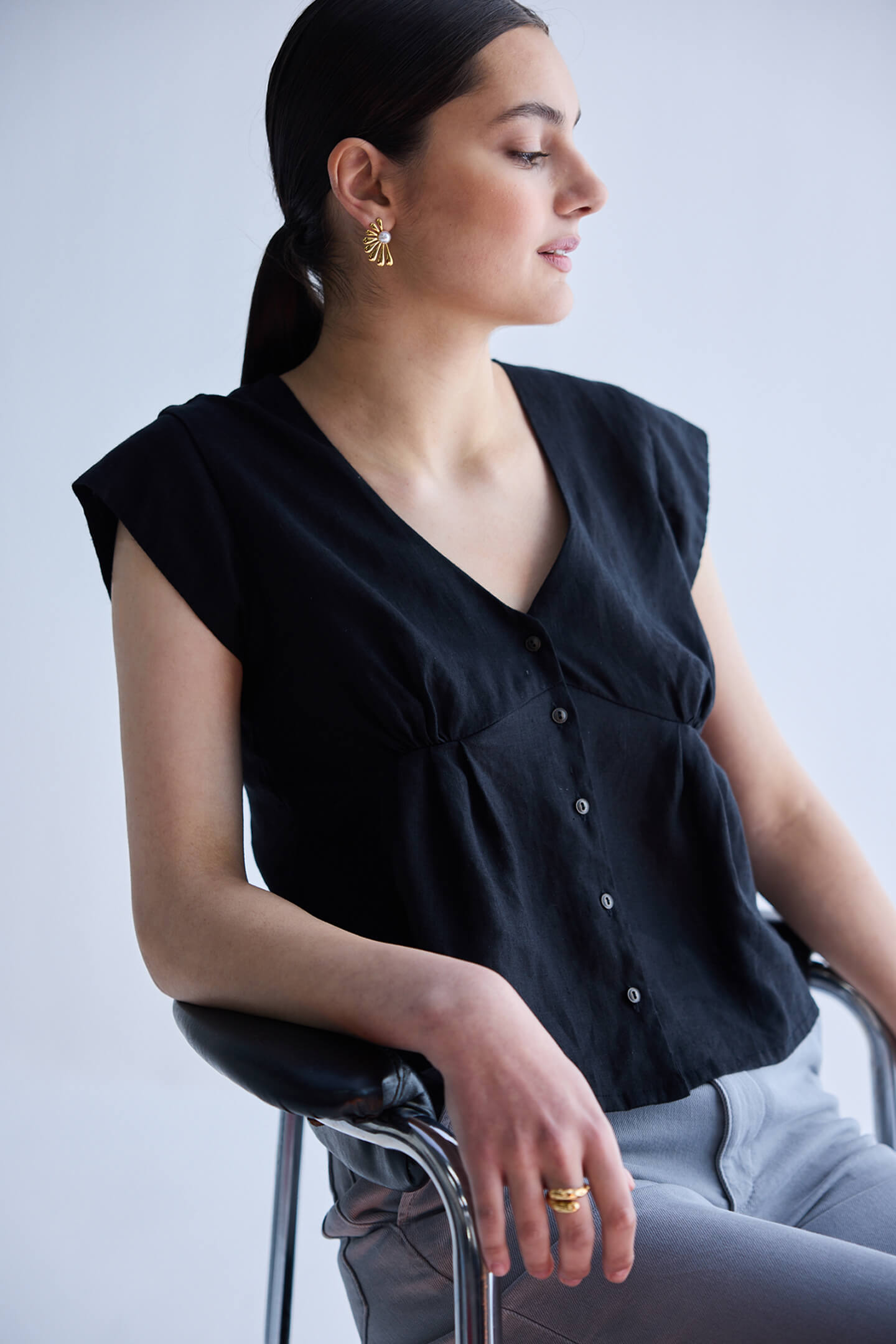 Deep V-neck short top in Black by reistor featuring cap sleeves, front button detailing, and breathable lightweight fabric in a relaxed fit design.