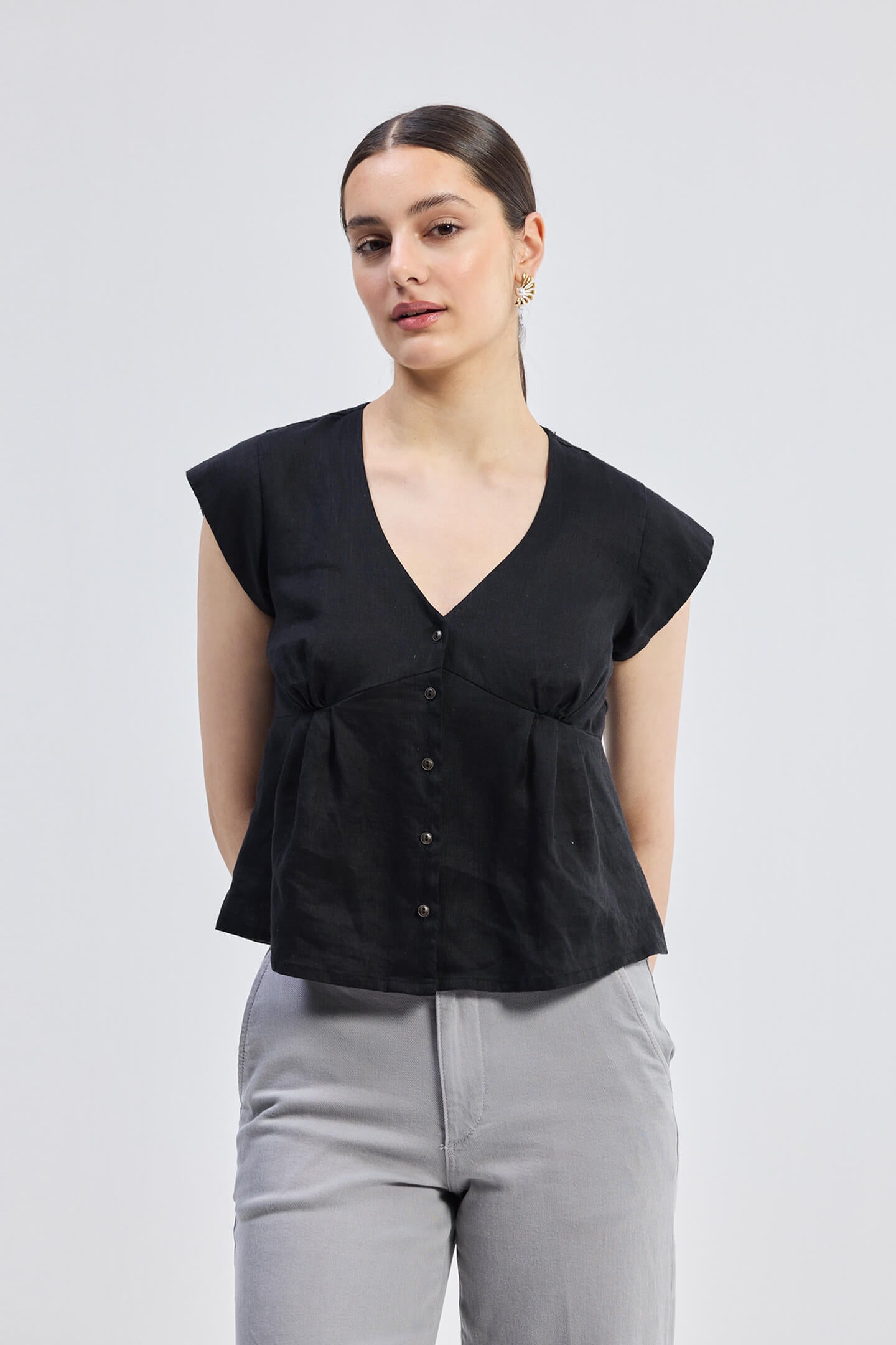 Deep V-neck short top in Black by reistor with cap sleeves, front button closure, and breathable linen fabric in a relaxed fit silhouette for everyday wear.