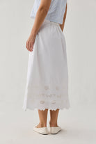 White skirt with lace details worn by a person on a plain background