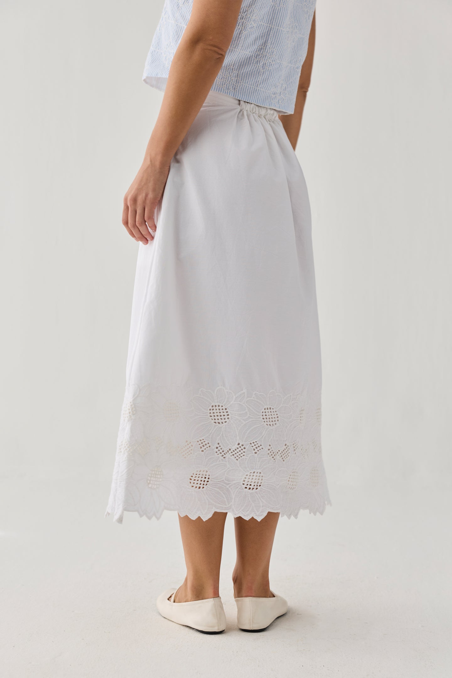 White skirt with lace details worn by a person on a plain background