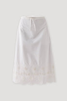 White embroidered midi skirt with a relaxed A-line silhouette, adjustable drawstring waistband, and intricate cutwork embroidery along the scalloped hem, displayed against a light background.