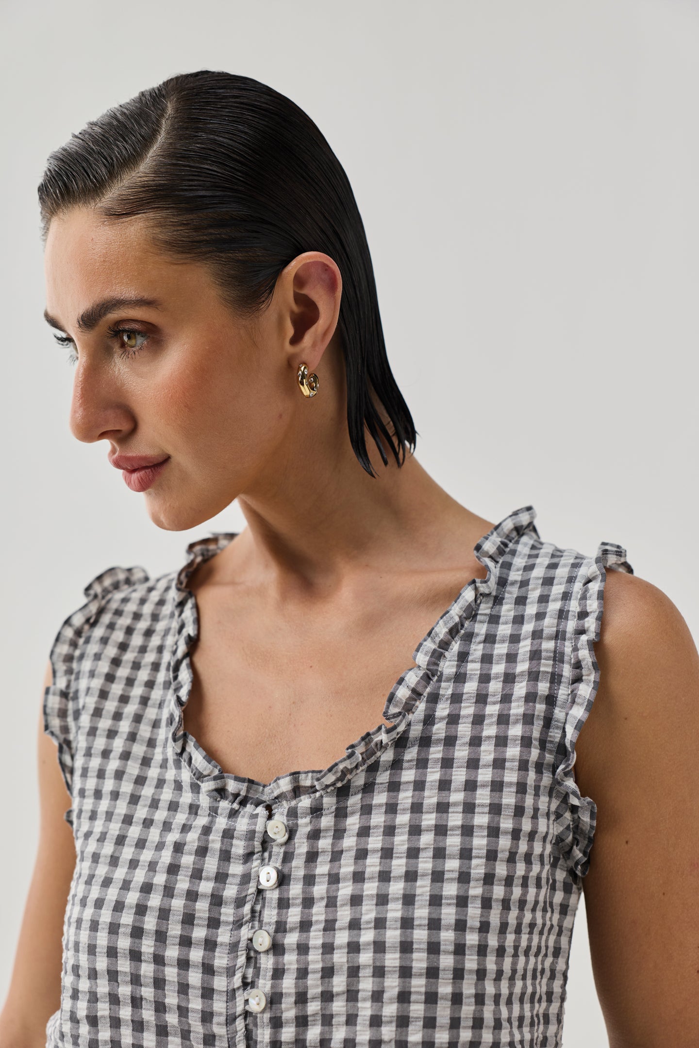 Close-up of Embroidered Peplum Top in Grey Check by Reistor with ruffle neckline