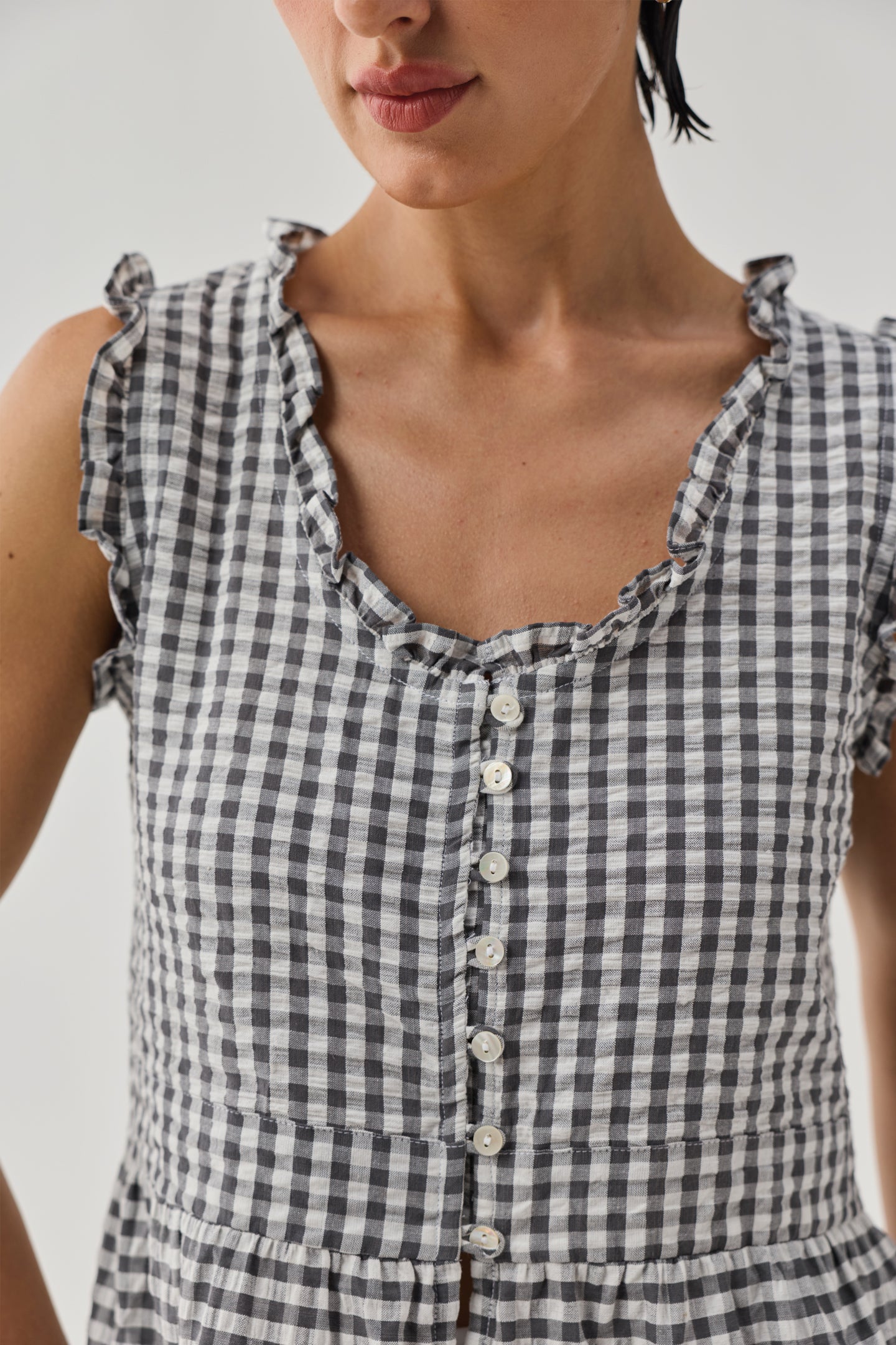 Detailed view of grey check embroidered peplum top with textured fabric