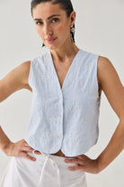 Embroidered Sleeveless Vest Top in Blue Stripe featuring delicate floral embroidery, a textured striped pattern, V-neckline, and button-front design, shown in a close-up view and paired with a white skirt.