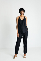 Woman wearing the Reistor Endless Sunday Top in Black, a sleeveless sustainable top paired with black pants, featuring a relaxed fit for effortless everyday style.