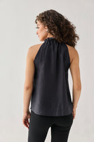 Woman wearing a black sleeveless top against a plain background