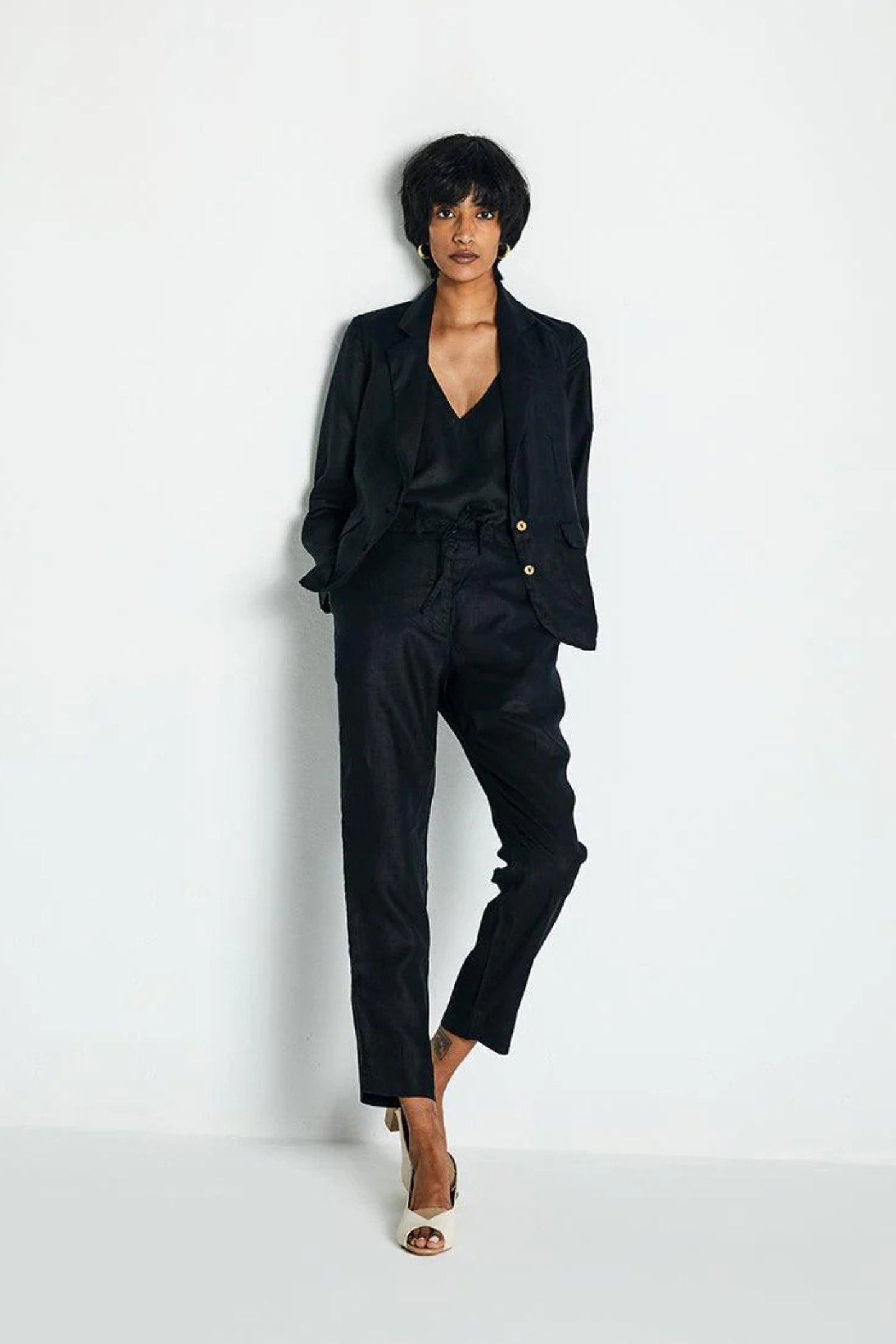 Person wearing a black suit by Reistor on a white background, featuring a tailored fit, timeless design and modern minimalist style.