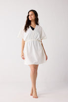Woman wearing a white dress against a plain background