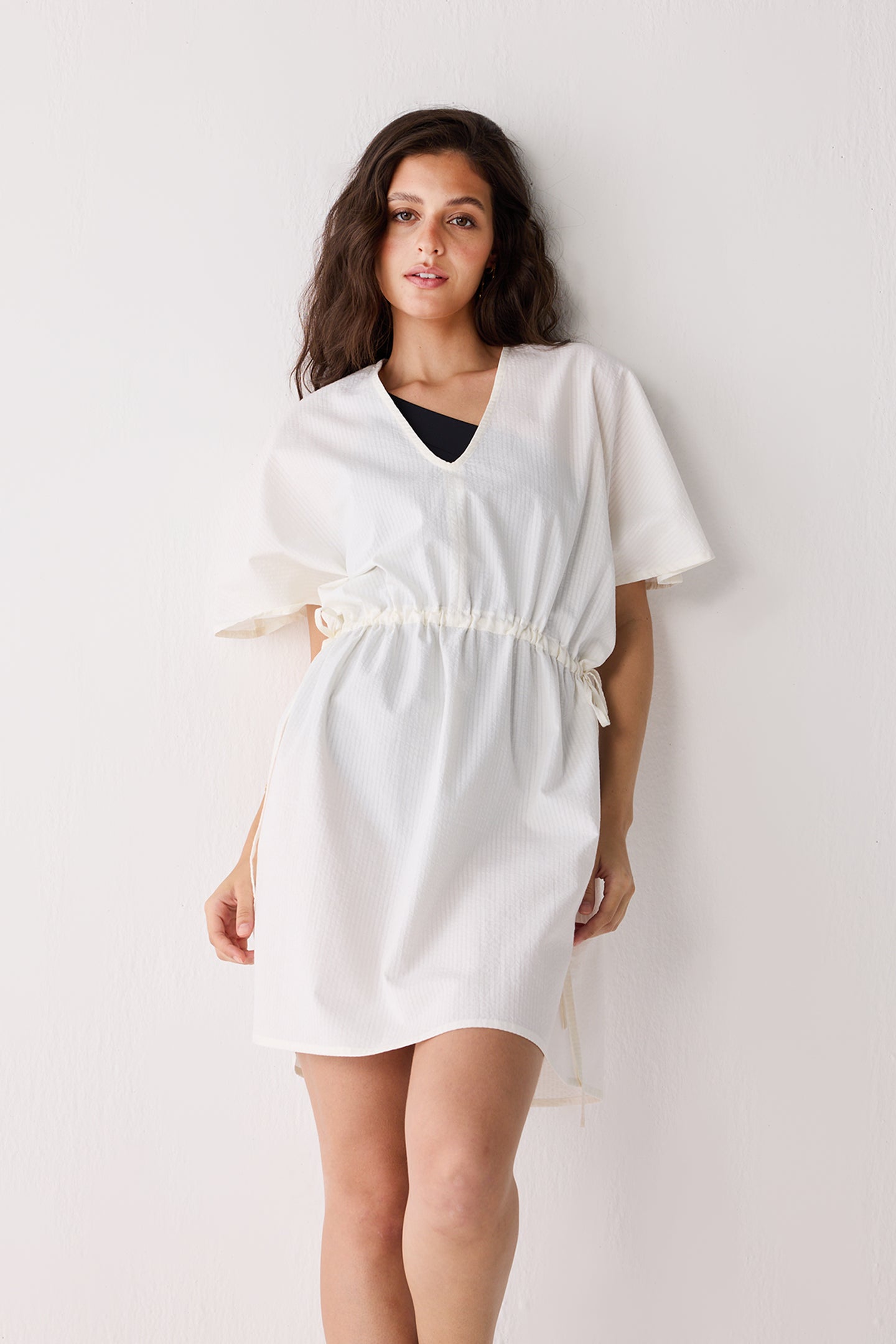 Woman wearing a white dress against a plain background