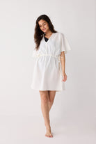 Woman wearing a white dress with a belt on a plain background