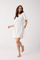 Woman wearing a white dress on a plain background
