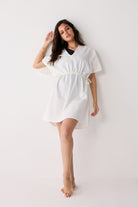 Woman wearing a white dress against a plain background